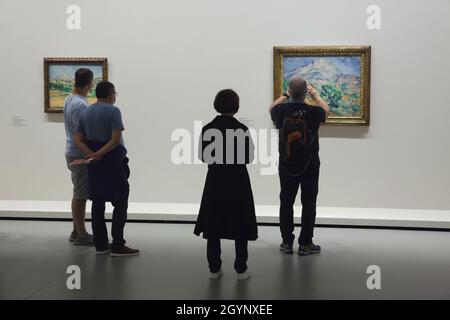 Besucher vor den Gemälden des französischen modernistischen Malers Paul Cézanne, die in der Ausstellung "Ikonen der modernen Kunst aus der Morozov Collection" in der Fondation Louis Vuitton in Paris, Frankreich, ausgestellt wurden. Gemälde "die Ebene von Mont Sainte-Victoire. Blick von Valcros (1882-1885) und Mont Sainte-Victoire (1896–1898) von Paul Cézanne von links nach rechts. Die Ausstellung zur Sammlung Morozov läuft bis zum 22. Februar 2022. Stockfoto