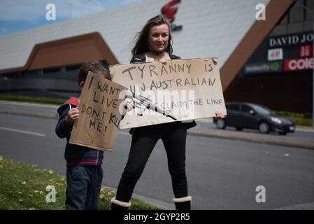 Melbourne, Australien, 9. Oktober 2021. Eine Mutter und ihr Kind halten bei einer Anti-Lockdown-Kundgebung am Straßenrand Schilder hoch, das Kind hält auch eine Spielzeugwaffe. Quelle: Jay Kogler/Alamy Live News Stockfoto