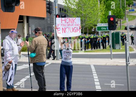 Melbourne, Australien, 9. Oktober 2021. 'Hupen, wenn du genug hast'. Ein Anti-Lockdown-Protestler hält ein Schild, während ein anderer interviewt wird, wobei Polizeibeamte im Begriff sind, einzugreifen, als Teil einer Kundgebung am Straßenrand auf der Springvale Road. Quelle: Jay Kogler/Alamy Live News Stockfoto