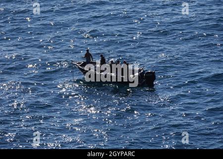 Vier Männer in einem Fischerboot auf einem glitzernden Ozean Stockfoto