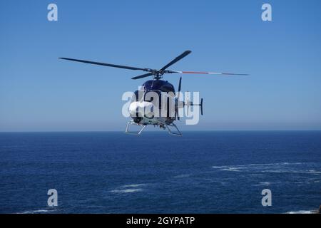 NSW Police Helicopter, der über dem Ozean kreist Stockfoto