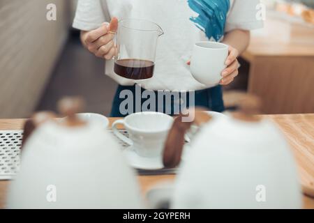 Barista mit Glaskrug und einer Tasse Kaffee Stockfoto