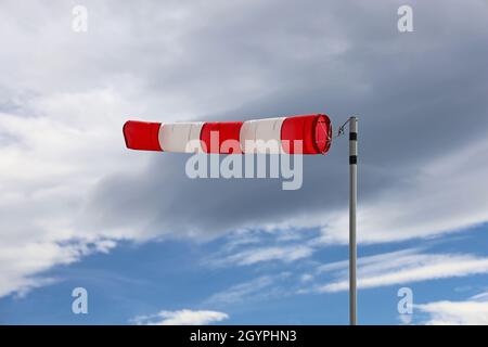 Nahaufnahme der roten und weißen Windsocken-Anzeige am bewölkten Himmel Stockfoto