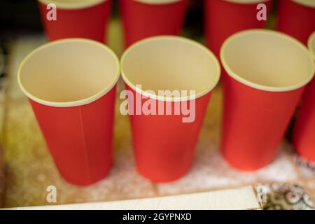 Leere Gläser. Rote Trinkbecher. Verteilung von Kaffee. Tisch mit Getränken. Papierutensilien. Stockfoto