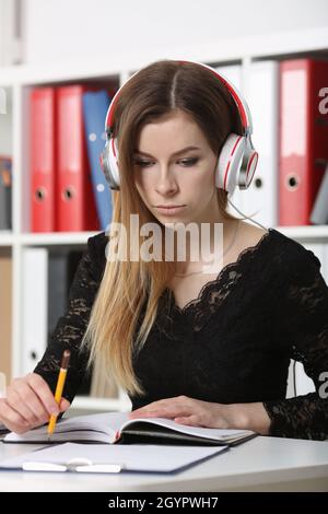 Blonde Frau hört Musik, schaut Filme online und lernt Stockfoto
