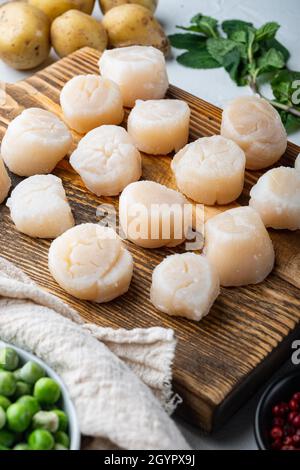 Meeresdelikatessen, Jakobsmuscheln mit Kartoffeln, grüner Erbse und Minze, auf weißem Strukturhintergrund Stockfoto