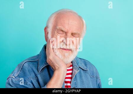 Porträt von attraktiven depressiven grauhaarigen Mann berühren Wangenzähne Schmerzen isoliert über hellen blaugrünen Hintergrund Stockfoto