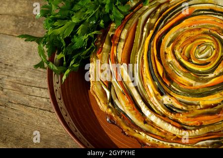 Gemüsekuchen mexikanische Sonne. Runde, offene Torte aus Zucchini, Auberginen und Karotten. Nahaufnahme von oben. Gesunde pflanzliche Lebensmittel. Vegetarismus. Spiralherb mit Auberginen. Stockfoto