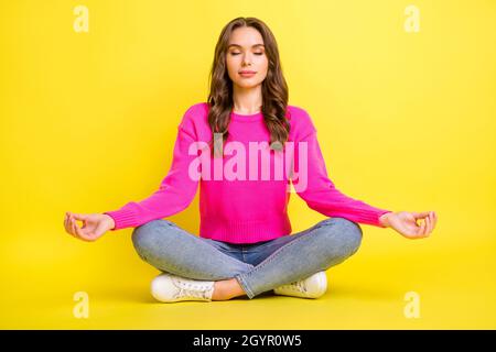 Foto in voller Größe von jungen attraktiven schönen entspannten friedlichen Mädchen sitzenden Boden tun Yoga isoliert auf gelbem Hintergrund Stockfoto