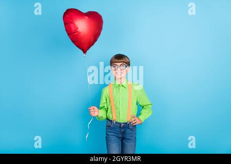 Foto Porträt kleiner Junge halten Herz geformten Luftballon in Hemd Gläser isoliert pastellblau Hintergrund Stockfoto