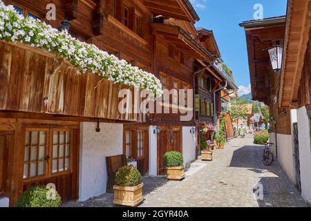 Idyllische Hintergasse mit gemütlichen alten Chalets in Saanen, Berner Oberland, Schweiz Stockfoto