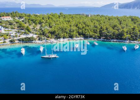 Luftbild von Segelbooten, die in der blauen Bucht von Fiskardo, Insel Kefalonia, Ionisches, Griechenland angedockt sind Stockfoto