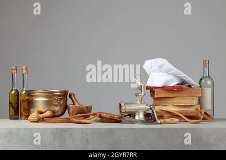 Kochmütze, alte Kochbücher und alte Küchenutensilien auf dem Küchentisch. Speicherplatz kopieren. Stockfoto