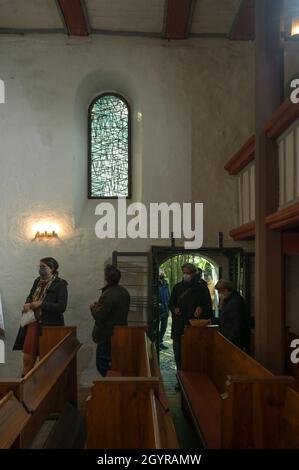 Sachsen Anhalt, Deutschland. Oktober 2021. 09. Oktober 2021, Sachsen-Anhalt, Altjeßnitz: In der kleinen romanischen Kirche im Landschaftspark Altjeßnitz, die vom Künstler B. Muhr entworfen wurde, passieren Besucher eines der drei neuen Buntglasfenster. Diese neuen Fenster sind Teil des Projekts „Lichtungen“ der Evangelischen Landeskirche Anhalt, das zeitgenössische Glasmalerei in die historischen Kirchen Anhalts bringt. Die Fenster wurden bereits im vergangenen Jahr mit Unterstützung der Landeskirche Anhalt und der Ecclesia Foundation installiert, konnten aber aufgrund der Corona-Pandemie bis jetzt nicht eingeweiht werden. Ph Stockfoto