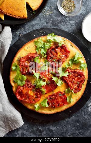 Gesunde Pizza (vegan und glutenfrei) aus Kichererbsenmehl mit Tomate auf blauem Steingrund. Draufsicht, flach liegend Stockfoto