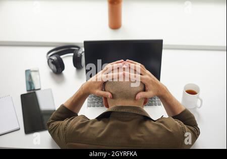 Gestresster und müder Mann machte sich Sorgen wegen Problemen und Fehlern, die er mit einem Laptop am Schreibtisch saß Stockfoto