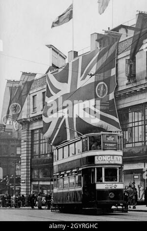 Werbung für Matratzen vor einem Doppeldecker-Trolleybus auf einer Rundstrecke im Stadtzentrum von Leeds, unter dem riesigen Union Jack, der am 12. Mai 1937 die Krönung des britischen Monarchen König George VI. Feiert Stockfoto