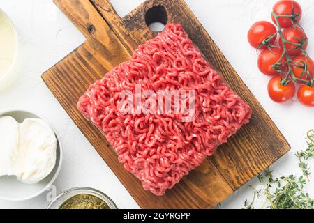 Hausgemachtes Hackfleisch in einer schwarzen Schüssel mit Zutaten. Fresh Raw Hackfleisch zum Kochen Fleischbällchen Set, auf weißem Steingrund, Draufsicht flach liegend Stockfoto
