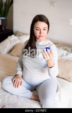 Eine Schwangerin überprüft ihren Blutzucker mit einem Blutzuckermessgerät. Stockfoto