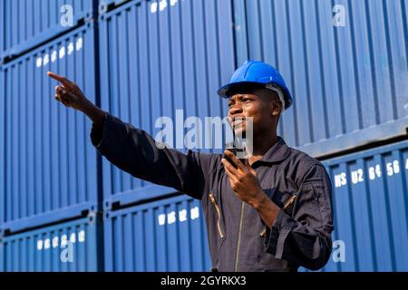 Schwarzer afrikanischer Amarikaner Mann Arbeiter Kontrolle Verladung Frachtcontainer an kommerziellen Schiffahrtsdock. Fracht Fracht Dock und Import Export logistic Stockfoto