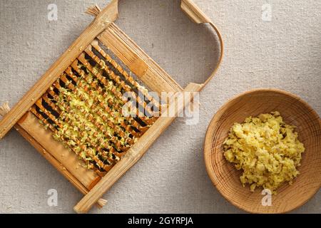 Frisches Ingwergranulat in Waschbrett und Holzplatte, frischer Ingwer auf der Wäsche Stockfoto