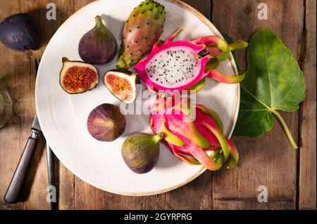 Draufsicht auf frisch geschnittene Drachenfrüchte (Pitahaya) und gewöhnliche Feigenfrüchte auf einem weißen Teller Stockfoto