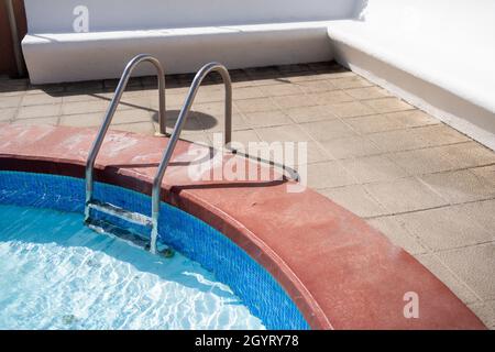 Silberne Leiter, die in einen Pool in einem Garten führt Stockfoto
