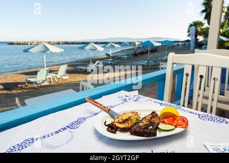Ein Gericht mit gegrilltem Oktopus auf dem Tisch einer Taverne am Wasser in Katelios, Kefalonia, Ioanischen Inseln, Griechenland Stockfoto