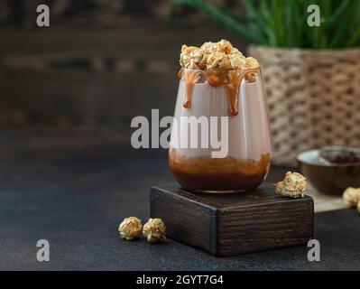 Milchshake mit Karamellsauce, verziert mit Karamellpopcorn und Schokoladenpulver auf grünem Hintergrund. Platz für Text kopieren. Stockfoto