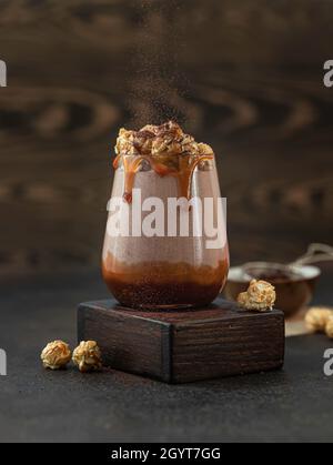 Milchshake mit Karamellsauce, verziert mit Karamellpopcorn und Schokoladenpulver auf grünem Hintergrund. Platz für Text kopieren. Stockfoto