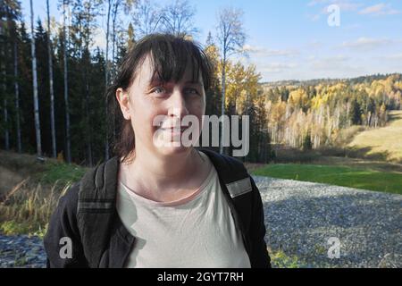 Eine lächelnde frau mittleren Alters aus europa steht im Wald. Stockfoto