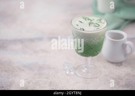 Kalter grüner Matcha-Tee mit Eiswürfel und Milch. Gesunde Ernährung Konzept. Milch in ein Glas grünen Tee gießen. Mit Kopierplatz für Text. Stockfoto