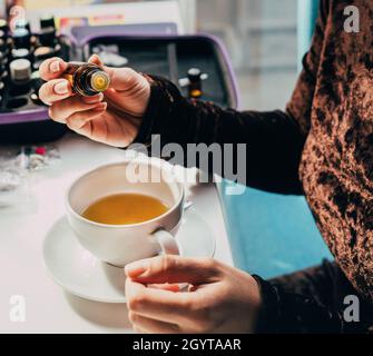 Hinzufügen von gesundem Öl in einem Obst Kräutertee Hände aus nächster Nähe Stockfoto