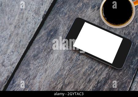 Draufsicht auf Mockup schwarz-weißen Bildschirm Handy-Smartphone mit einer Tasse Kaffee auf alten Holztisch Hintergrund. Overhead View Phone Flat Lay and Copy Stockfoto