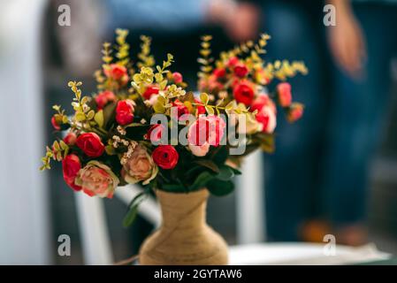 Schöne rote Rosenblüten in der braunen Vase mit dunklem Hintergrund grünen Blättern vorhanden Stockfoto