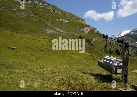 Vorrichtung zum Transport von Milchbehältern mit Riemenscheibe. Landtechnik auf Weiden in den Höhenalpen der Schweiz. Speicherplatz kopieren. Stockfoto