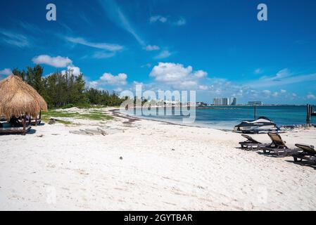 Strand, Boot, Liegestühle und Baldachin mit Gebäude gegen bewölkten Himmel Stockfoto