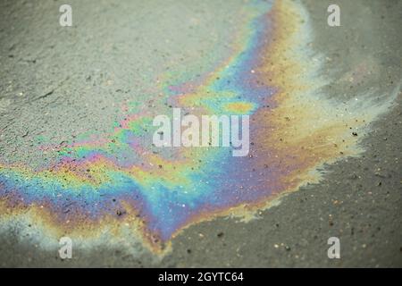 Ein Benzinfleck auf dem Asphalt. Spur von verschüttetem Kraftstoff. Alle Farben in brennbaren Flüssigkeiten. Stockfoto