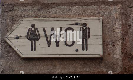 WC-Schild oder Logo der öffentlichen Toiletten aus Holz an der alten Stadtmauer Stockfoto