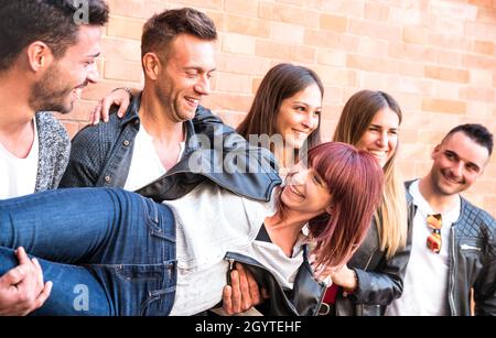 Multikulturelle Jungs und Mädchen tausendjährig halten Freundin und echten Spaß an der Backsteinmauer in der Stadt - Urban Jugend Konzept mit jungen Stockfoto