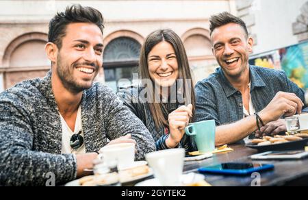 Fröhliche Freunde, die im Pub-Restaurant mit Cappuccino und heißem Tee reden und Spaß haben - Junge Leute zusammen in der Mode-Cafeteria - Freundschaftsconce Stockfoto