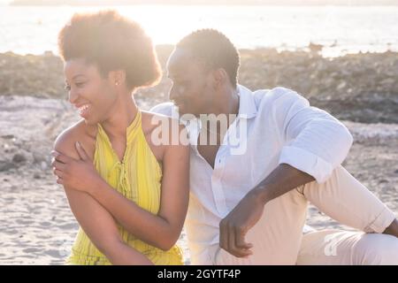 afroamerikanisches Paar, das am Strand am Meer sitzt und sich entspannt. Glückliches schwarzes Paar, das Zeit im Freien verbringt. afroamerikanischer Mann und Frau enjoyi Stockfoto