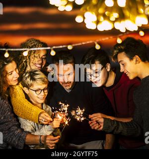 Familie feiert brennendes Funkeln. Männer und Frauen haben Spaß zusammen. Eltern mit Kindern, die brennende Funkeln halten, feiern das neue Jahr, c Stockfoto