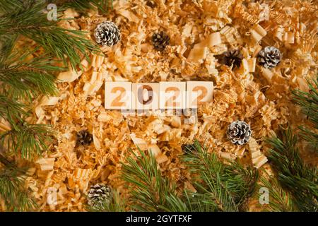 Holznummern 2022 Würfel symbolisieren die Feier des neuen Jahres. Kiefernzapfen und Holzhackschnäbel in der Nähe von Kiefern Stockfoto