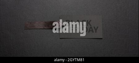 Schwarzer Friday Sale Text Schriftzug auf Preisschild, dunkler Hintergrund. Spezielle saisonale Angebote Schild, Karton Papierkarte und Satinband, Banner Stockfoto