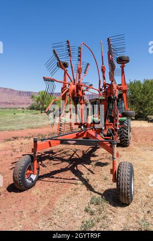 Ein Drehrechen kombiniert kleinere Heureihen zu einer größeren Reihe, um die Anzahl der für die Ballenpresse erforderlichen Durchgänge zu reduzieren. Stockfoto