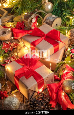 Geschenkboxen mit roten Bändern, Weihnachtsbaumspielzeug und Lichtern. Frohe Weihnachten und Frohes neues Jahr. Seitenansicht, vertikal. Stockfoto