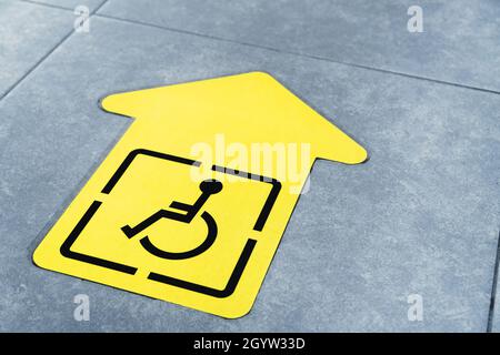 Gelber Pfeil für Behinderte auf der Fliese des Warteraumes am Flughafen. Stockfoto