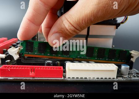 Jemand installiert RAM in einen Steckplatz auf der Hauptplatine eines PCs. Stockfoto