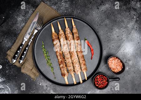 Gegrillter Lula Kebab auf Spieß mit Gewürzen, auf Teller, auf schwarzem dunklen Steinteller Hintergrund, Draufsicht flach liegend Stockfoto